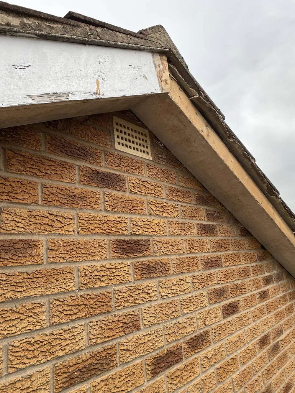 Gable end with rotten, unpainted timber boards, before