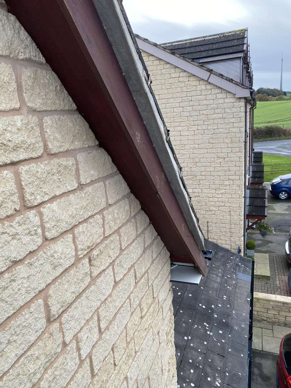 Brown timber bargeboard on a stone gable, before