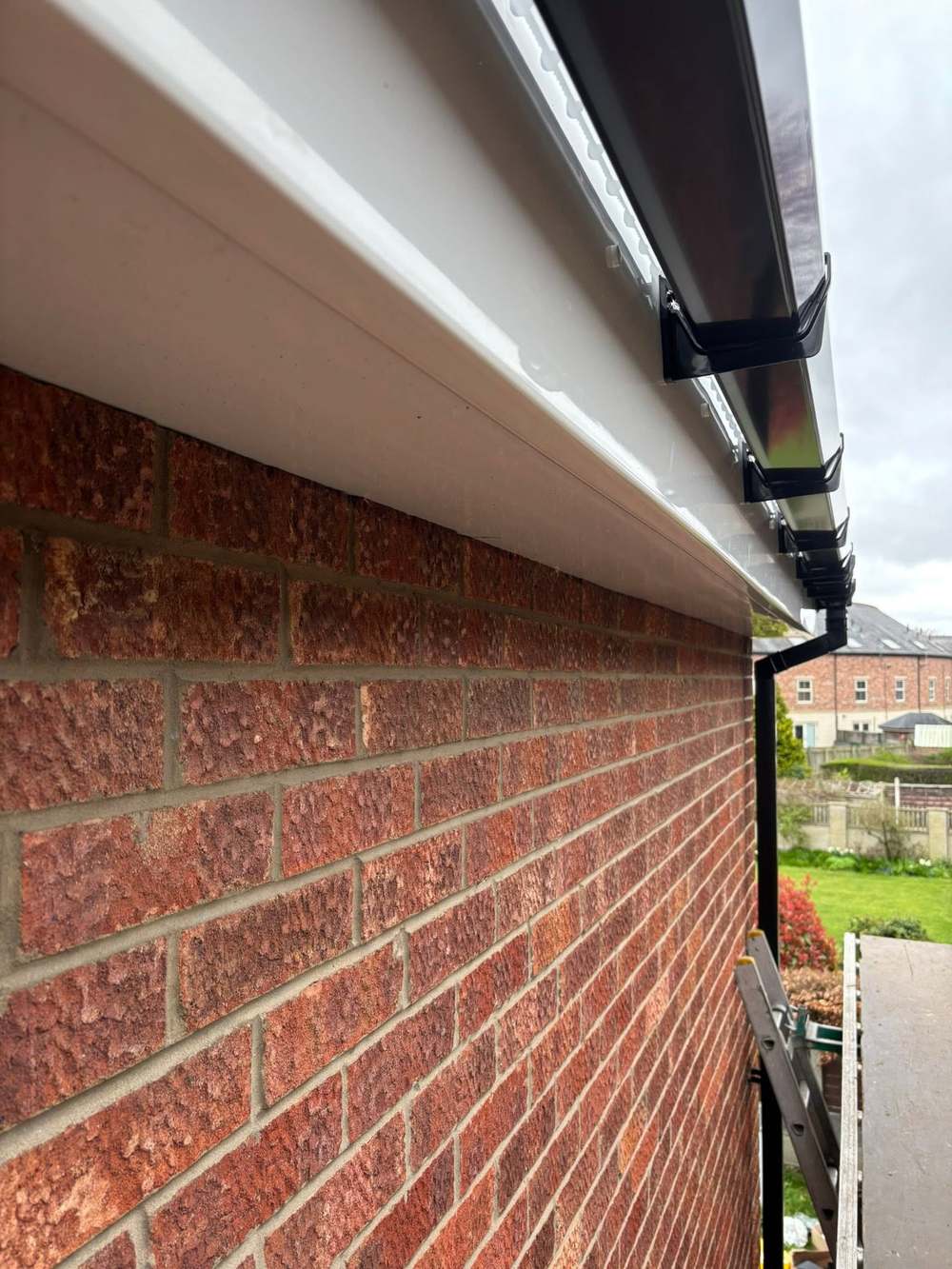 White fascia with a black gutter along red brick