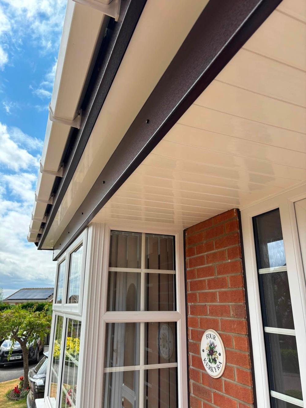 New white soffit and fascia seen from below against a blue summer sky